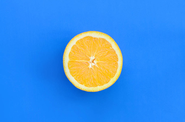 Top view of a one orange fruit slice on bright background in blu - Photo, Image