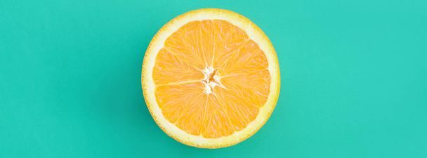 Pohled shora na jeden řez oranžové plody na světlé pozadí v tyrkysově zelené barvy. Nasycený citrusových textury obrazu - Fotografie, Obrázek