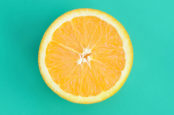 Vue de dessus d'une tranche d'un fruit orange sur fond lumineux de couleur vert turquoise. Une image de texture d'agrumes saturée
 - Photo, image