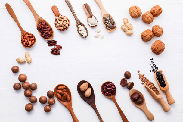 Spoon of various legumes and different kinds of nuts walnuts kernels ,hazelnuts, macadamia ,almond kernels,brown pinto ,red kidney beans and pecan set up on white wooden table. - 写真・画像