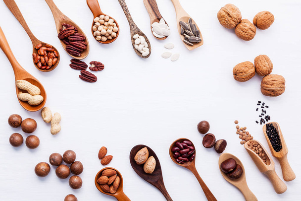 Spoon of various legumes and different kinds of nuts walnuts kernels ,hazelnuts, almond kernels,brown pinto ,red kidney beans and pecan set up on white wooden table. - Foto, afbeelding