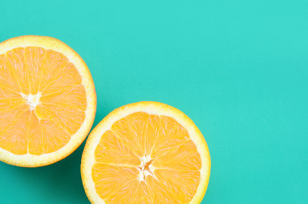 Вид зверху на кілька апельсинових фруктових скибочок на яскравому фоні в бірюзово-зеленому кольорі. Зображення насиченої цитрусової текстури
 - Фото, зображення