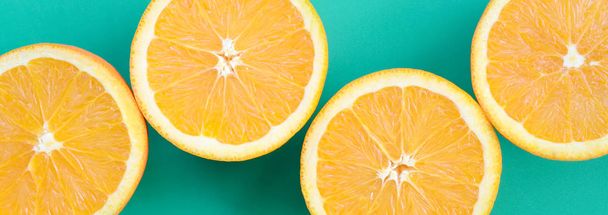 Top view of a several orange fruit slices on bright background in turquoise green color. A saturated citrus texture image - Photo, image