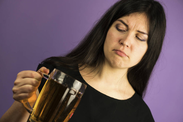 Cute Brunette Girl on a Purple Background Shows shis Dislike to Pint of Beer - Fotoğraf, Görsel