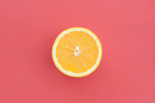 Top view of a one orange fruit slice on bright background in red color. A saturated citrus texture image - Foto, afbeelding