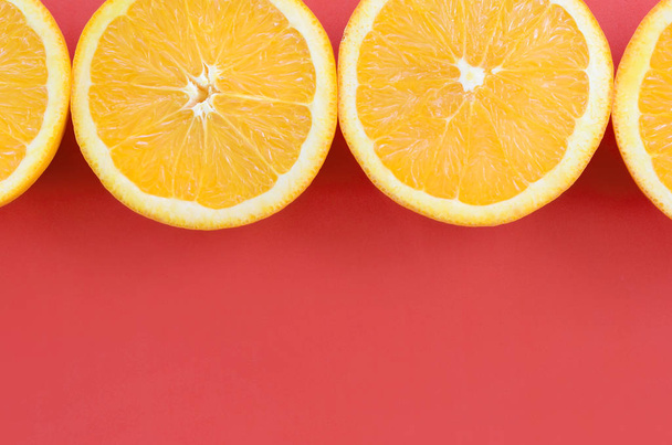 Vista dall'alto di diverse fette di frutta arancione su sfondo brillante di colore rosso. Un'immagine satura di texture di agrumi
 - Foto, immagini