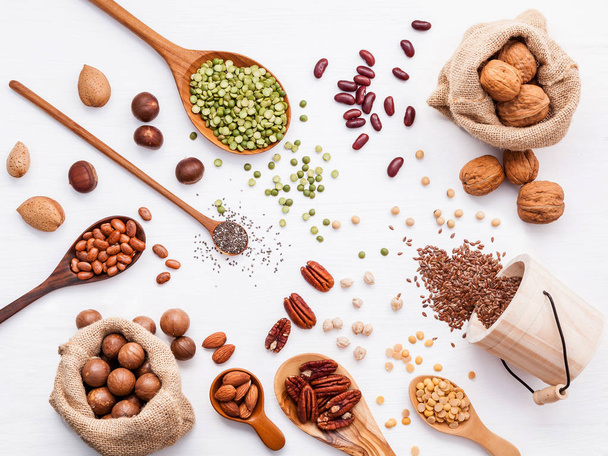 Various legumes and different kinds of nuts walnuts kernels ,hazelnuts, almond kernels,brown pinto ,soy beans ,flax seeds ,chia ,red kidney beans and pecan set up on white wooden table. - Foto, imagen