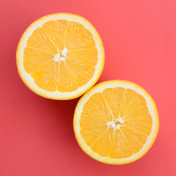 Draufsicht auf mehrere orangefarbene Fruchtscheiben auf hellem Hintergrund in roter Farbe. ein gesättigtes Zitrusbild - Foto, Bild