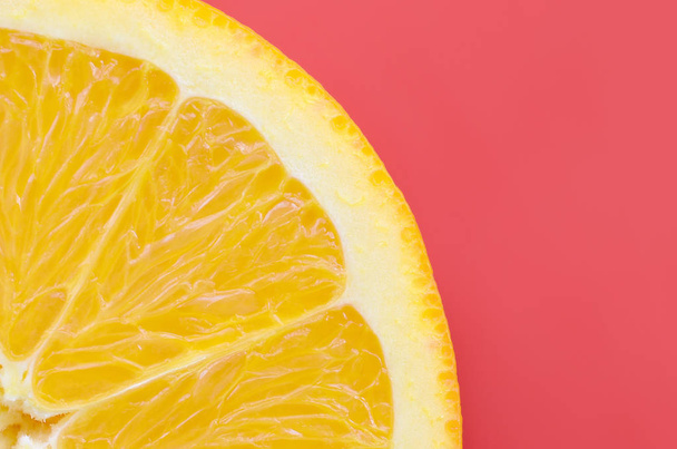 赤い色で明るい背景上のオレンジ色の果物のスライスを 1 つの平面図です。飽和の柑橘系テクスチャ画像 - 写真・画像
