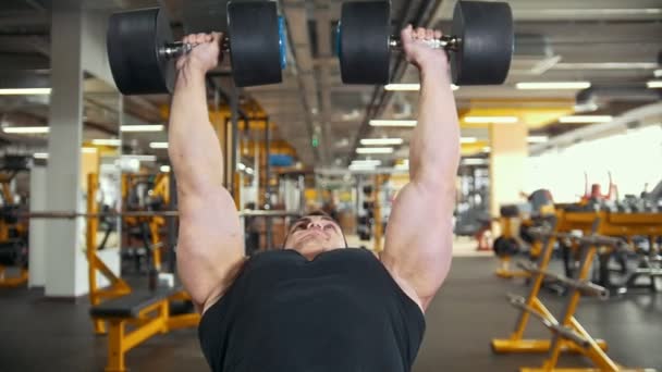 Gespierde bodybuilder oefent programma met halters in een kamer training - Video
