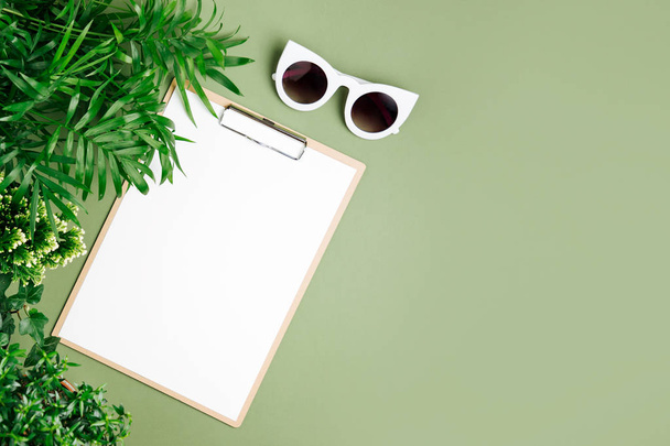 Tropical leaves, clipboard and sunglasses on green background. - Fotografie, Obrázek
