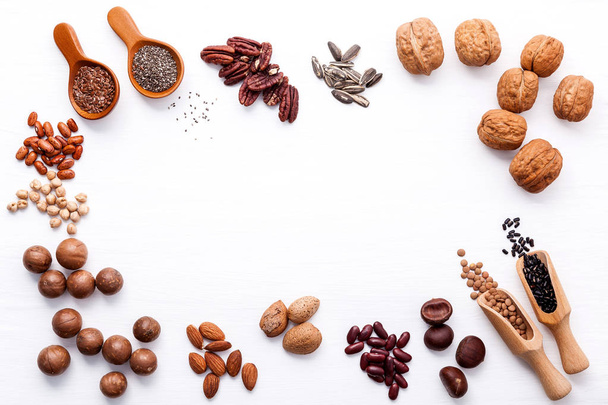 Spoon of various legumes and different kinds of nuts walnuts kernels ,hazelnuts, macadamia ,almond kernels,brown pinto ,red kidney beans and pecan set up on white wooden table. - Photo, Image