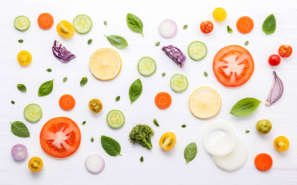 Potravinový vzor se surovinami ze salátu, listů salátu, okurek, rajčat, mrkve, brokolice, bazalky, cibule a citronu ležel na bílém dřevěném pozadí. - Fotografie, Obrázek