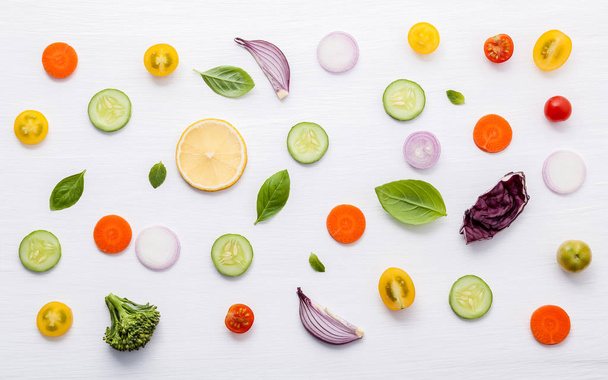 Wzór jedzenie surowych składników sałatki. Liście różnych warzyw sałata, ogórki, pomidory, marchew, brokuły, cebula i cytryny płaskie leżał na białym tle. - Zdjęcie, obraz