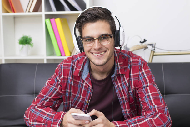 young adult or teenager with mobile phone and headphones at home - Foto, immagini