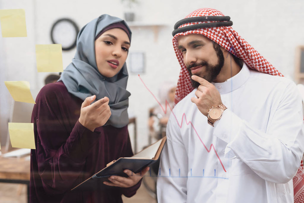 Arab man and woman taking notes on glass board in office - Foto, immagini