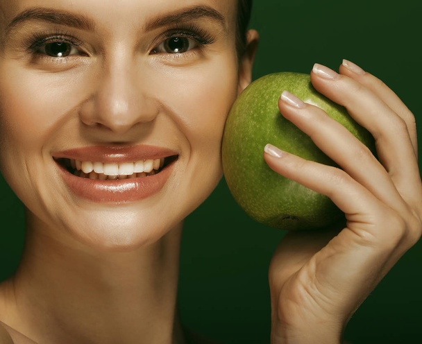Young woman with  green apple over green background - Foto, imagen