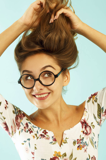 Funny pretty young woman in round glasses holding her hair up ov - Фото, зображення