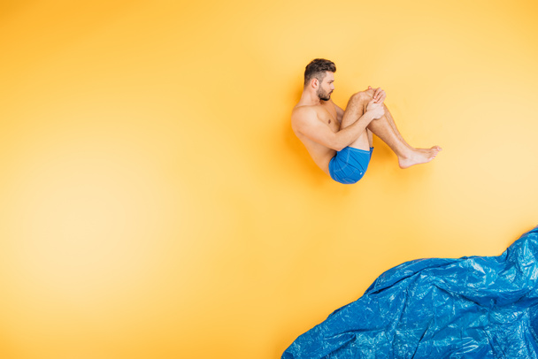 pohledný mladý muž v šortkách skákání v představit moře na žluté  - Fotografie, Obrázek