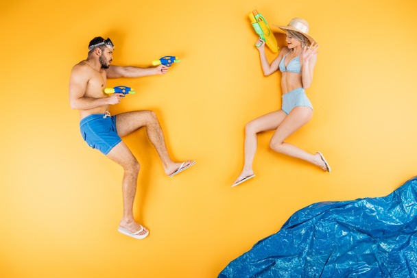 giovane coppia in costume da bagno giocare con pistole ad acqua su immaginare spiaggia, concetto di vacanza estiva
 - Foto, immagini