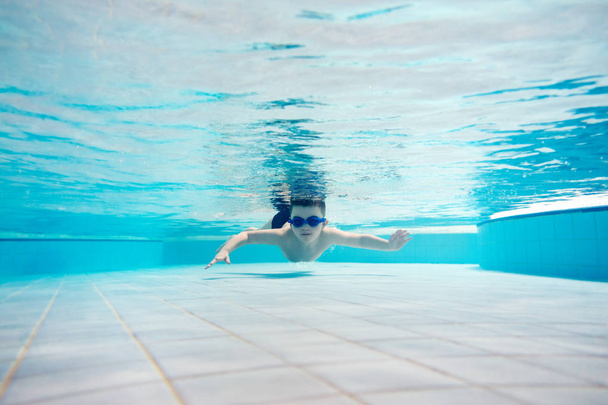Niño nadando bajo el agua con gafas de natación
. - Foto, Imagen
