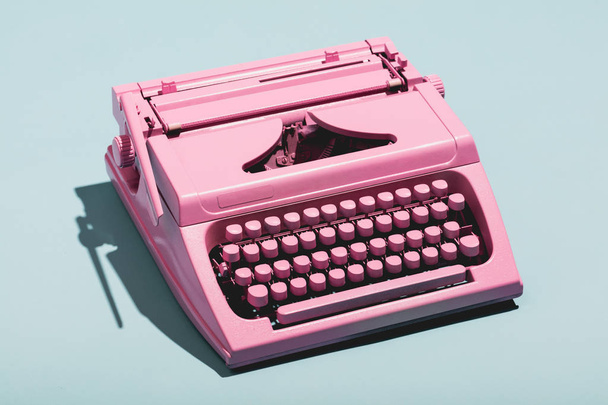 Máquina de escribir rosa sobre fondo pastel azul
. - Foto, Imagen