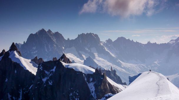 guia de montanha e cliente em um longo e estreito cume de neve wxposed com uma excelente vista da paisagem montesa circundante perto de Chamonix
 - Foto, Imagem