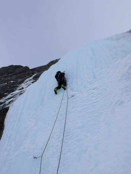escalador de hielo masculino en una empinada cascada en los Alpes suizos
 - Foto, Imagen