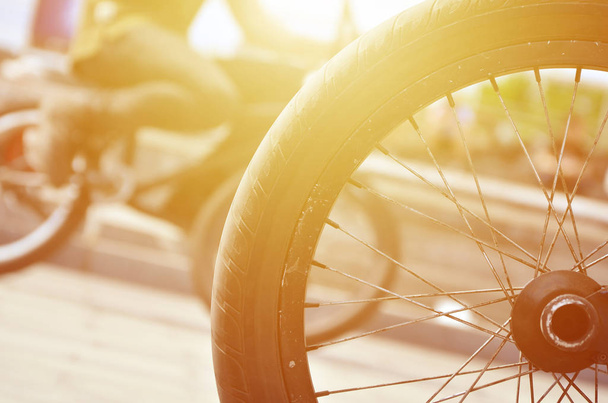 Una rueda de bicicleta BMX contra el telón de fondo de una calle borrosa con ciclistas. Concepto de deportes extremos
 - Foto, imagen
