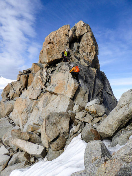 горный гид и клиент-мужчина на скалистом хребте направляются к высокой вершине во французских Альпах недалеко от Шамони
 - Фото, изображение