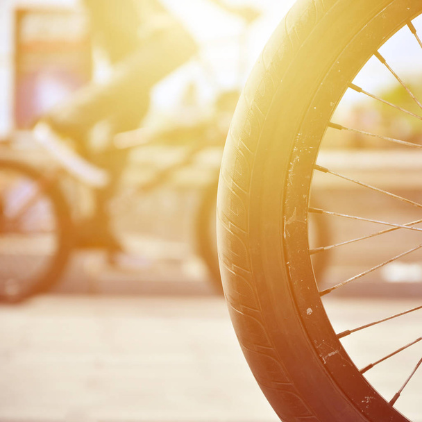A BMX bike wheel against the backdrop of a blurred street with c - Photo, Image