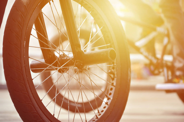 Uma roda de bicicleta BMX contra o pano de fundo de uma rua turva com ciclistas. Conceito de Esportes Extremos
 - Foto, Imagem