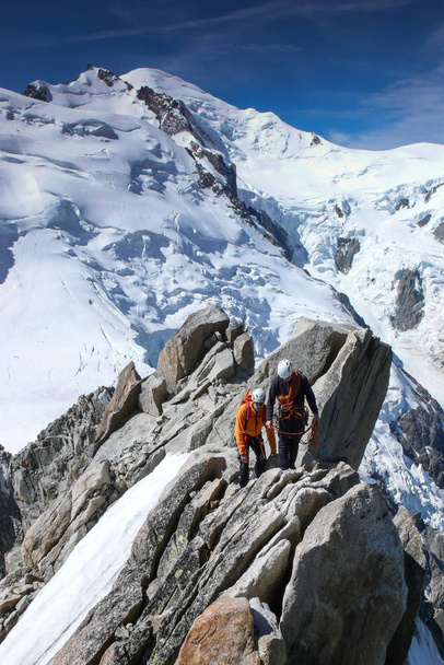Bergführer und ein männlicher Kunde auf einem felsigen Grat auf dem Weg zu einem hohen Gipfel in den französischen Alpen bei Chamonix - Foto, Bild