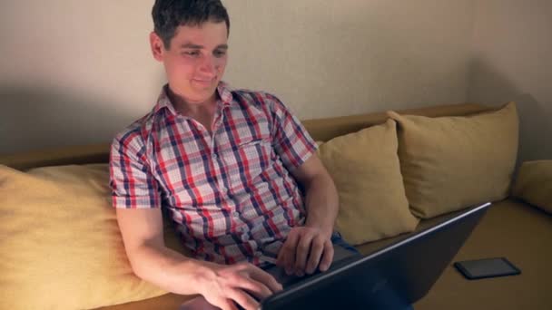 Young Man Using Laptop Surfing Internet Sits On Sofa Couch. Slow Motion 30p 0.5 Real Time Speed 60p - Záběry, video