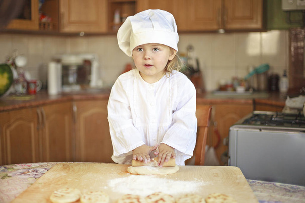 Kislány rakja a teszt, a kap a szakács, az ablakon, a konyhában. - Fotó, kép
