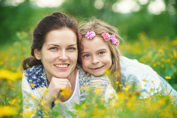 Mother and daughter on spring meadow with blooming flowers - Valokuva, kuva