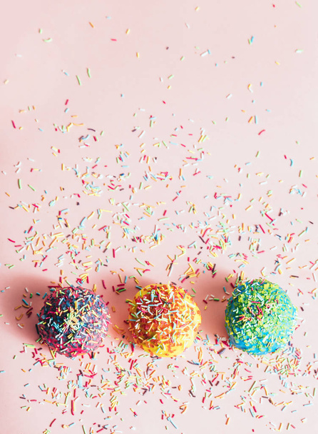 Drie kleine donuts met suiker strengen opleggen pastel roze achtergrond. - Foto, afbeelding