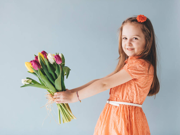 Young child holding bunch of freshly cut tulips. - Фото, зображення