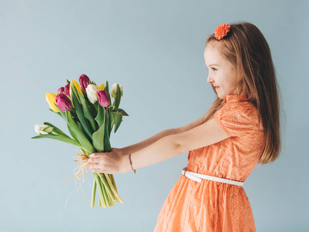 Young child holding bunch of freshly cut tulips. - Valokuva, kuva