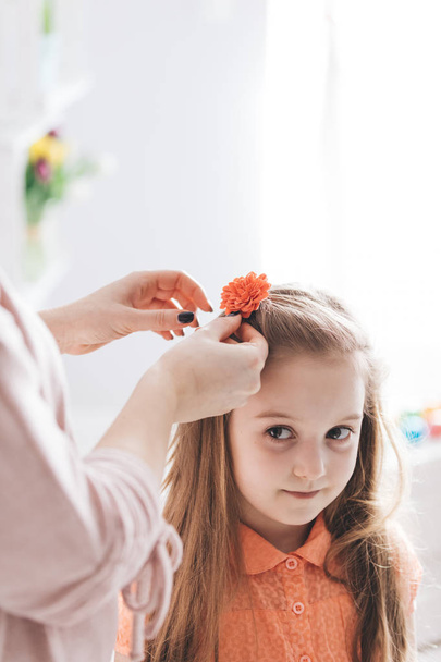 Mother clipping hair clip with red flower.  - Foto, Imagem