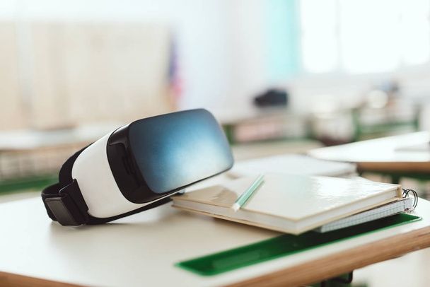 Foto de close-up de fone de ouvido de realidade virtual na mesa com manual e lápis em sala de aula
  - Foto, Imagem