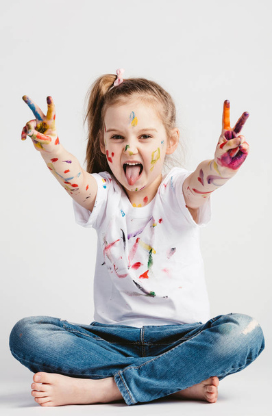 Girl showing victory sign with hands, sticking tongue out. - Photo, Image