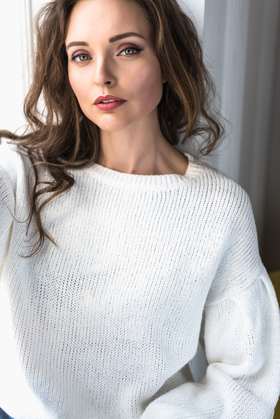 portrait of beautiful young brunette woman in white sweater looking at camera - Foto, Imagem