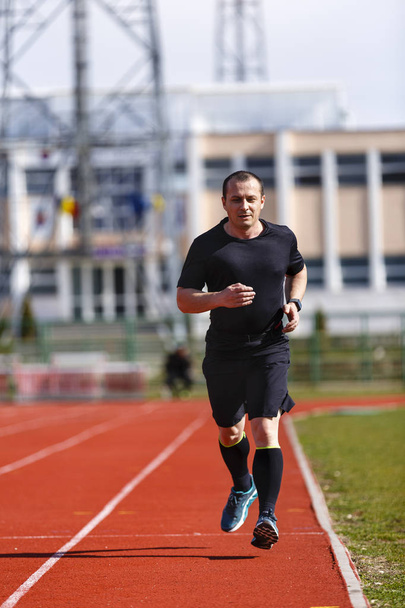 Male sprinter in middle age trains for race competition - Photo, Image