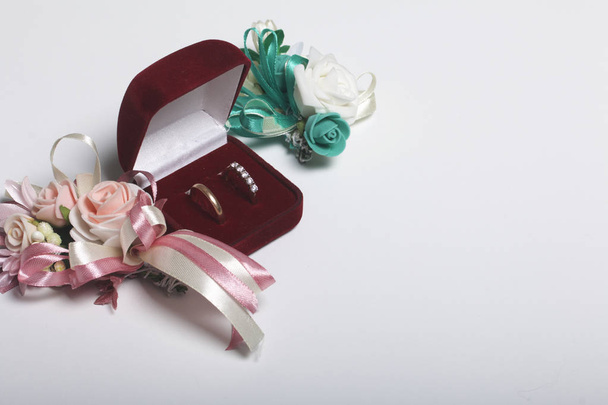 Wedding decor. Boutonniere groom with the bride, their wedding rings in box, lie on a white surface. - Fotó, kép