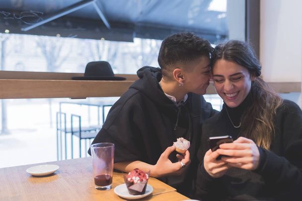 2人の女性レズビアンカップル屋内でスマートフォンを使って楽しむ-技術、愛、関係の概念 - 写真・画像