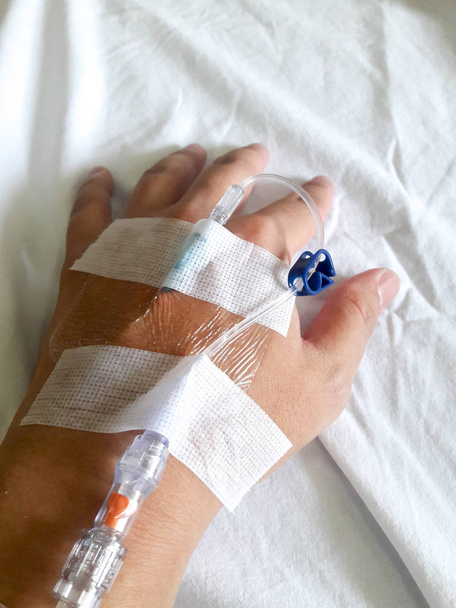 Patient hand with the tube of normal saline infusion on white cloth background - Φωτογραφία, εικόνα
