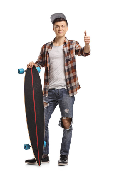 Full length portrait of a teenage hipster with a longboard making a thumb up sign isolated on white background - Фото, зображення
