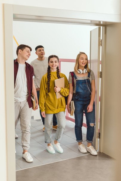 onnellinen teini lukiolaiset kävely koulun käytävällä
 - Valokuva, kuva