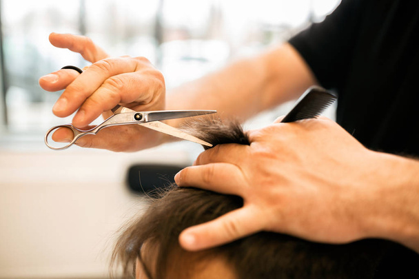 Las manos de un joven peluquero haciendo corte de pelo a un cliente atractivo de cerca
 - Foto, imagen